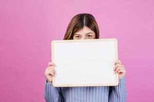 Portrait of Happy young woman holding an empty white placard over isolated pink background. photo