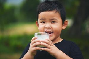 Little boy drinking milk in the park photo