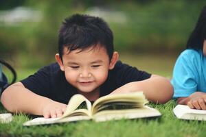 boy lying reading on grass field photo