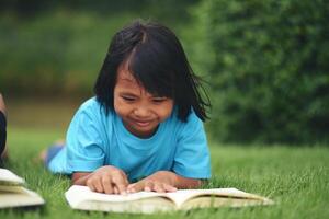 niña acostado leyendo en césped campo foto