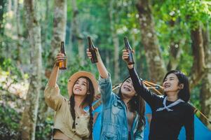 mujer joven anima y bebe bebidas frente a la tienda de campaña foto