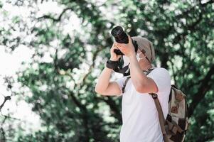 Asian traveler man with backpack taking a photo in the park