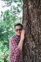 Portrait of Happy Asian man hugging a tree in forest photo