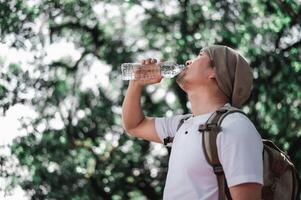 Portrait Asian traveler man with backpack drinking water photo