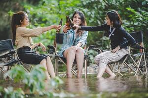 Group of women drink beer and soaked feet in stream photo