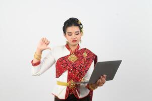 Portrait of Beautiful Thai Woman in Traditional Clothing Posing with laptop computer photo