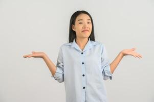 Portrait of confused young asian woman in blue shirt shrugging shoulders in bewilderment isolated on white background photo