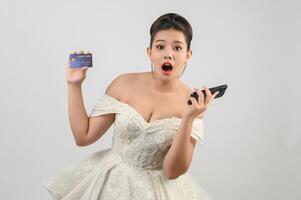 Young asian beautiful bride posting with credit card and smartphone in hand photo