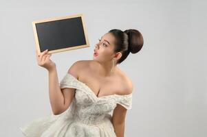 Young asian beautiful bride pose with blank blackboard in hand photo