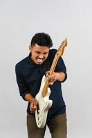 Portrait of Young Asian man in blue shirt with electronic guitar isolated on white background photo