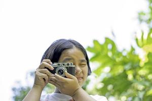 película cámara en el manos de un niña tomando un fotografía. verde arboles tocador telón de fondo.mujer tomando fotos con un cámara, selectivo enfocar, suave enfocar.