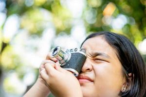 film camera in the hands of a girl taking a picture. Green trees boudoir backdrop.woman taking photos with a camera, selective focus, soft focus.