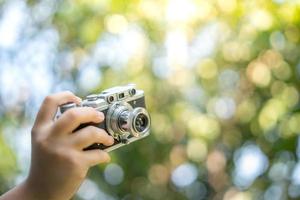 film camera in the hands of a girl taking a picture. Green trees boudoir backdrop.woman taking photos with a camera, selective focus, soft focus.