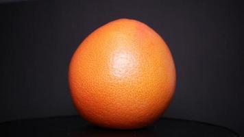 Ripe grapefruit on a black background rotates video