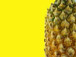 haft of pineapple on yellow background photo