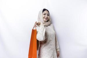 Portrait Asian Muslim woman happy beautiful young standing excited holding a shopping bag, studio shot isolated on white background photo