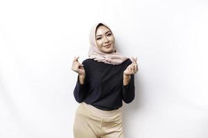 A happy young Asian woman wearing hijab feels romantic shapes heart gesture expresses tender feelings photo