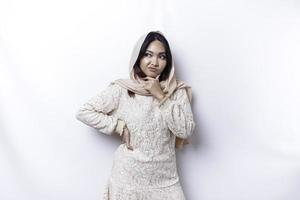 A thoughtful young Asian Muslim woman wearing hijab while looking aside, isolated by a white background photo