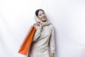 Portrait Asian Muslim woman happy beautiful young standing excited holding a shopping bag, studio shot isolated on white background photo