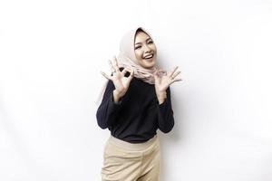 Portrait of a smiling Asian Muslim woman, giving an OK hand gesture isolated over white background photo