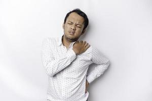 Tired upset young man wears white shirt suffering from pain, muscle spasm at workplace. Fatigue, deadline, pain and incorrect posture photo