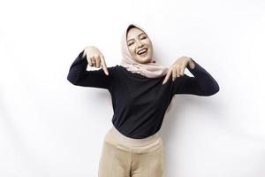Excited Asian Muslim woman hijab pointing at the copy space below her, isolated by white background photo