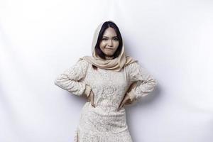 A dissatisfied young Asian Muslim woman looks at the camera posing on a white background, disgruntled girl with irritated face expressions show negative attitude photo