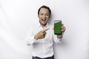 A portrait of a smiling Asian man wearing a white shirt and showing green screen on her phone, isolated by white background photo