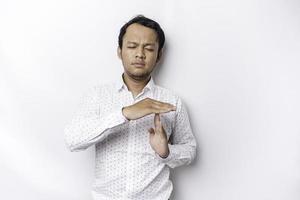 Hispanic man wearing white shirt doing time out gesture with hands, frustrated and serious face photo