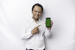 A portrait of a smiling Asian man wearing a white shirt and showing green screen on her phone, isolated by white background photo