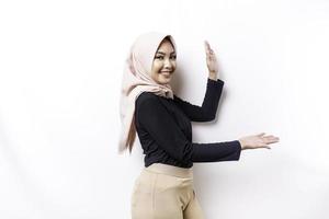 Young Asian Muslim woman smiling while pointing to copy space beside her photo