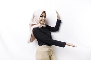 Young Asian Muslim woman smiling while pointing to copy space beside her photo