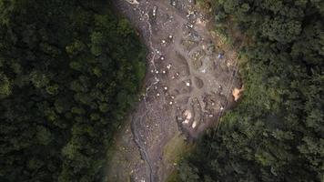 Aerial view of forest and river flowing cold lava of Mount Merapi and visible sand miners at work