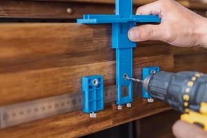 carpenter use a cabinet hardware jig adjustable punch locator drill guide sleeve for Install cabinet handles and knobs ,DIY maker and woodworking concept. selective focus photo