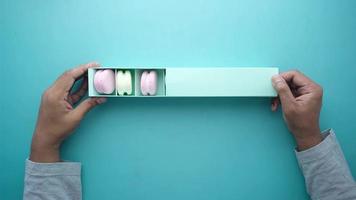 Macaroon in a paper box on light green background video