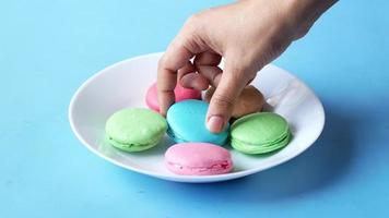 Hand pick macaroon on blue background with copy space video