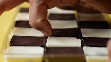 Hand wählen dunkel und Weiß Schokolade im ein Box auf Gelb Hintergrund video