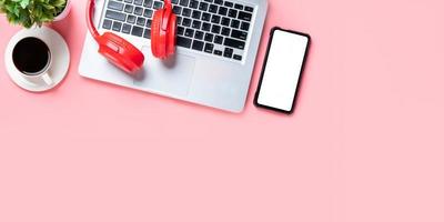 Office desk with laptop computer, Blank screen smart phone, headphone, cup of coffee on pink background, Top view , Mock up. photo