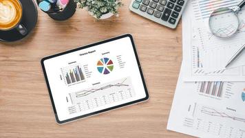 Tablet with charts and reports on office desk workplace. Top view flat lay photo