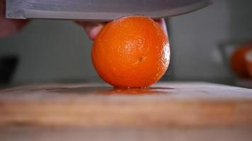 Cutting an orange close up on a wooden board video