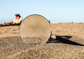 Magnifying glass in the sand photo