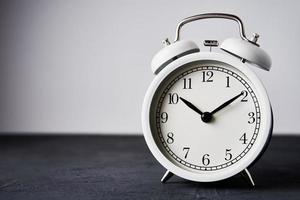 White vintage alarm clock on a black background with copy space photo