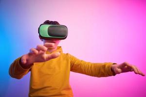 Boy with virtual reality glasses on colorful background. Future technology photo