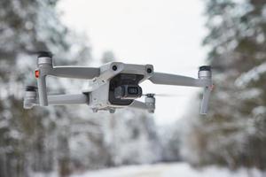 Drone quadcopter with camera flying in winter forest photo