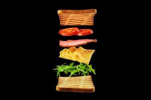 Fresh sandwich with flying ingredients on black background isolated photo