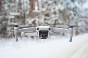 Drone quadcopter with camera flying in winter forest photo