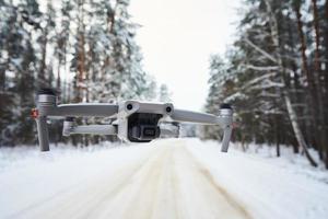 Drone quadcopter with camera flying in winter forest photo