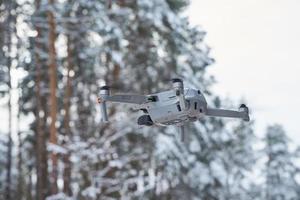 Drone quadcopter with camera flying in winter forest photo