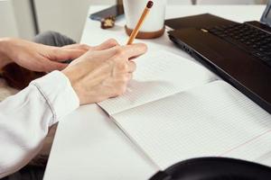 Woman makes notes in notebook and using laptop for study. photo