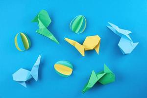conejos de origami de papel y huevos de colores sobre fondo azul foto